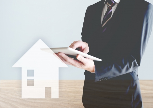 家の絵とパッドを持った男性