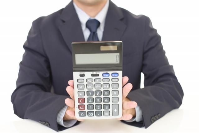 電卓を見せるスーツを着た男性